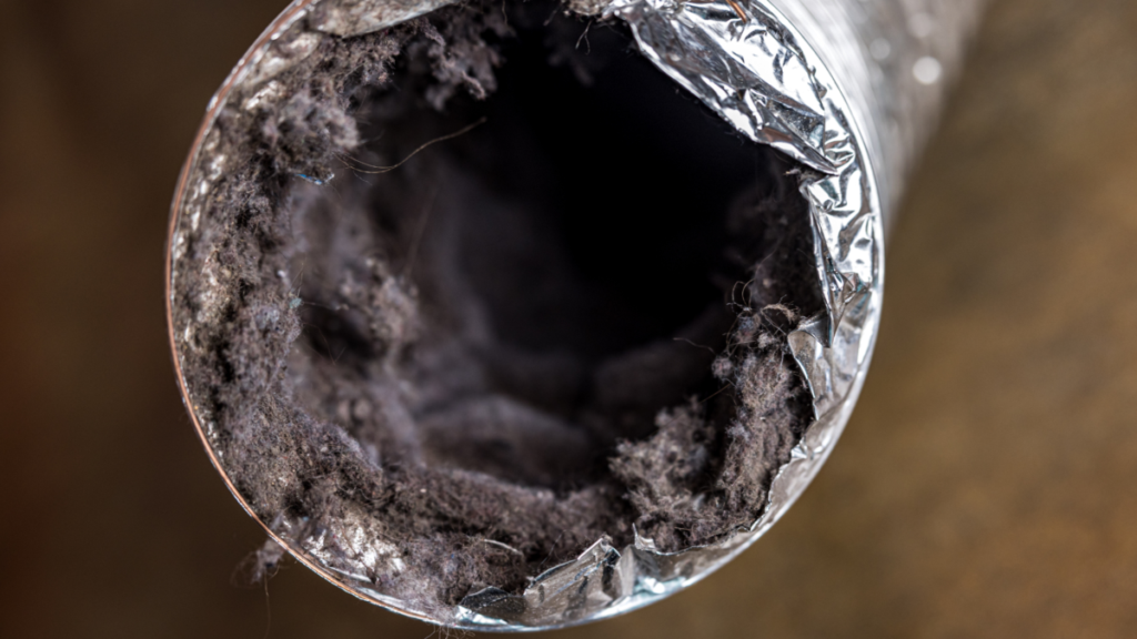 Close-up interior view of a flexible aluminum dryer vent duct heavily clogged with accumulated lint and debris along the inner walls.