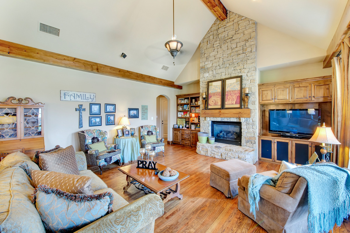 Custom luxury living room featuring a rustic stone fireplace and slanted ceilings.