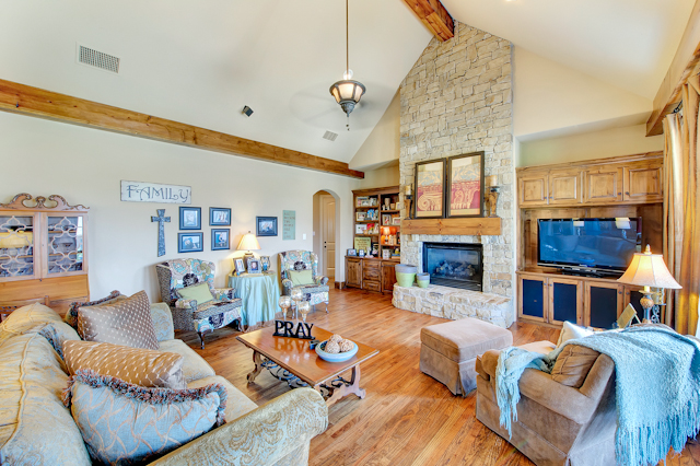 Custom luxury living room featuring a rustic stone fireplace and slanted ceilings.