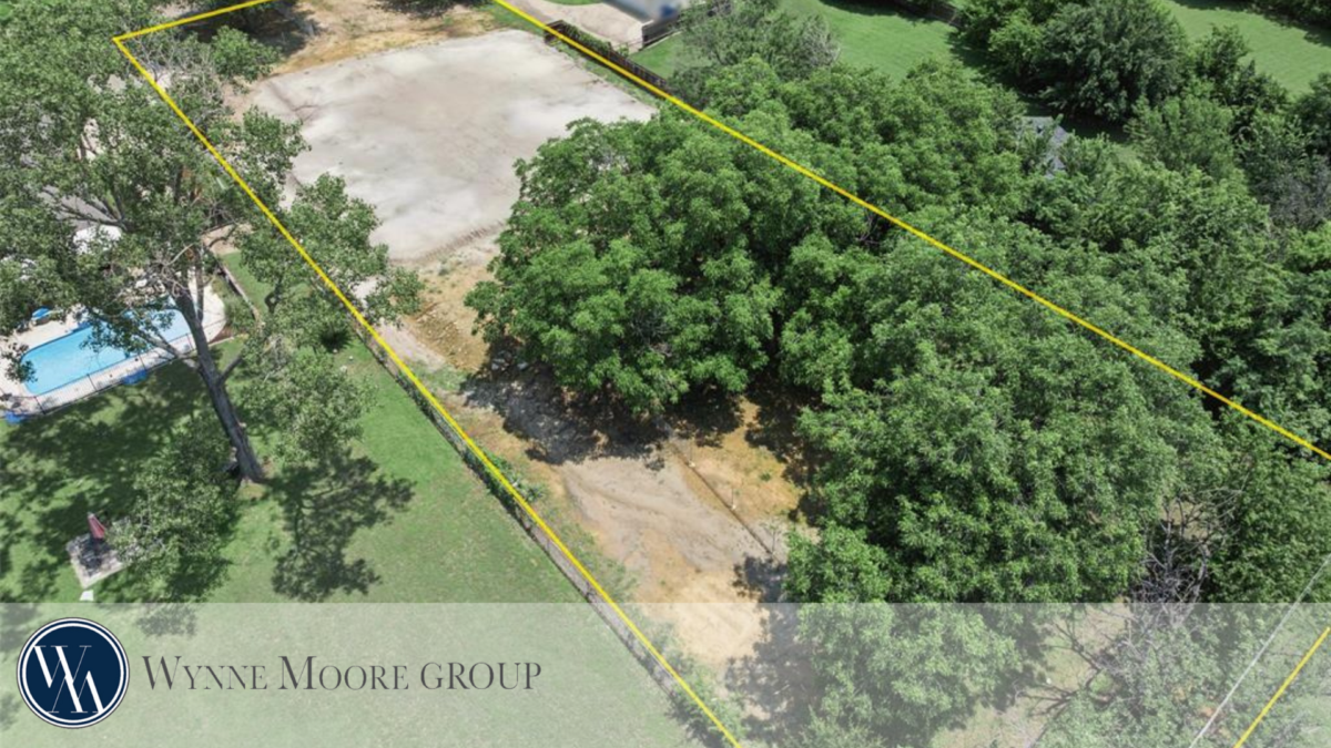 Aerial view of a residential lot outlined in yellow, showing cleared land and surrounding trees