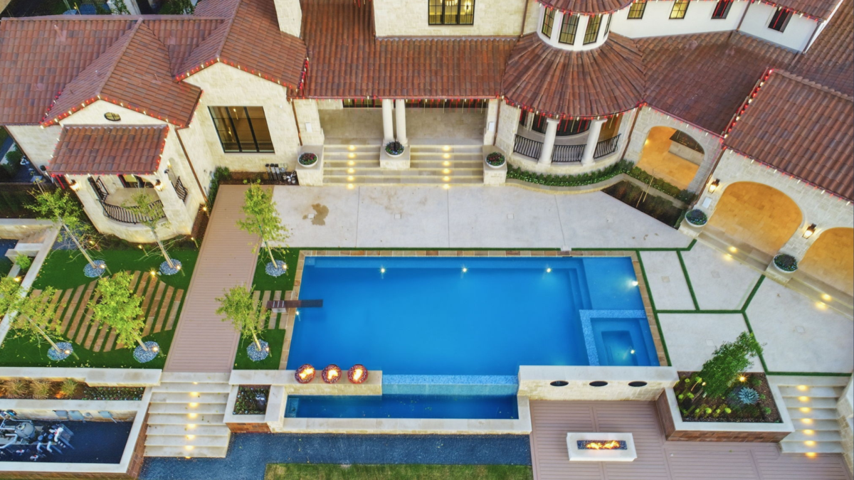 Overhead view of a luxury outdoor living space with pool, terraces, fire features, and landscaped walkways