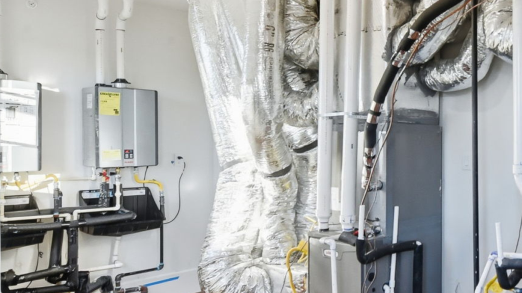 Tankless water heater and insulated mechanical systems installed in a garage, showing equipment that requires protection during freeze events.