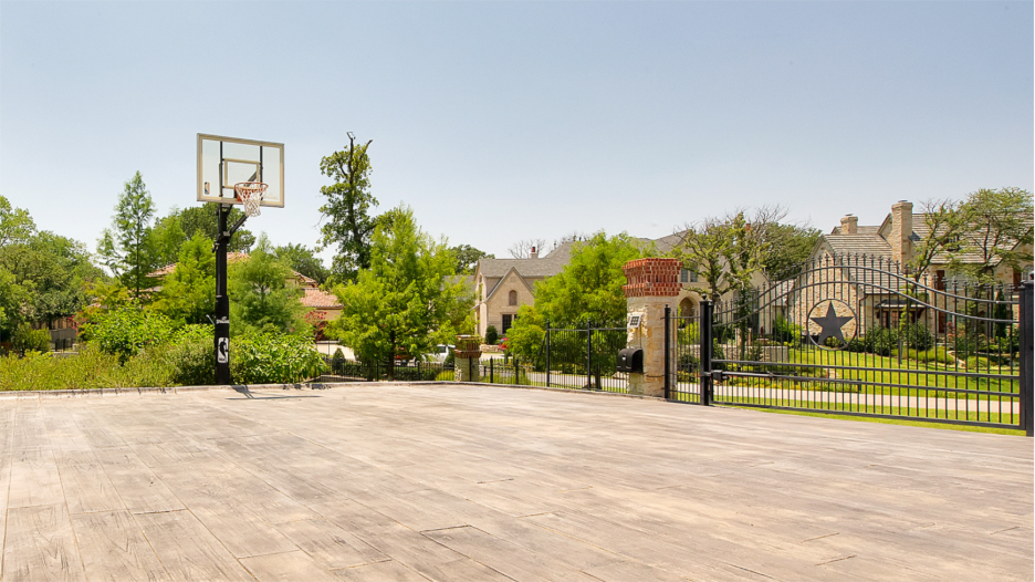 Custom driveway with basketball hoop and rod iron motorized driveway gate.