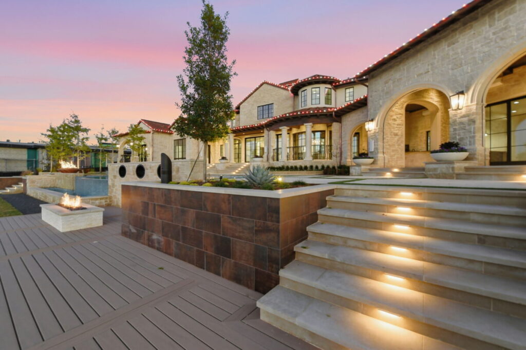 Luxury outdoor living space with fire pit, agave plant, and sage tree as accent garden beds around pool.