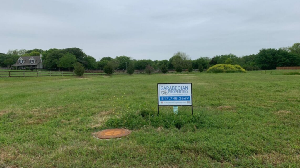 Empty residential lot with Garabedian Properties sign on it.
