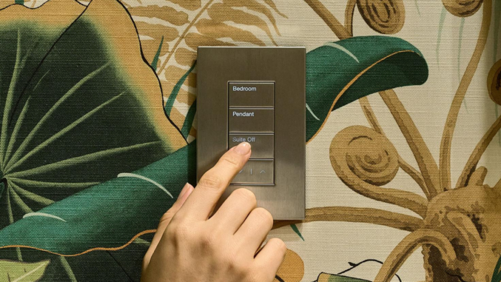 Finger pressing Lutron HomeWorks keypad labeled bedroom, pendant, and suite off.