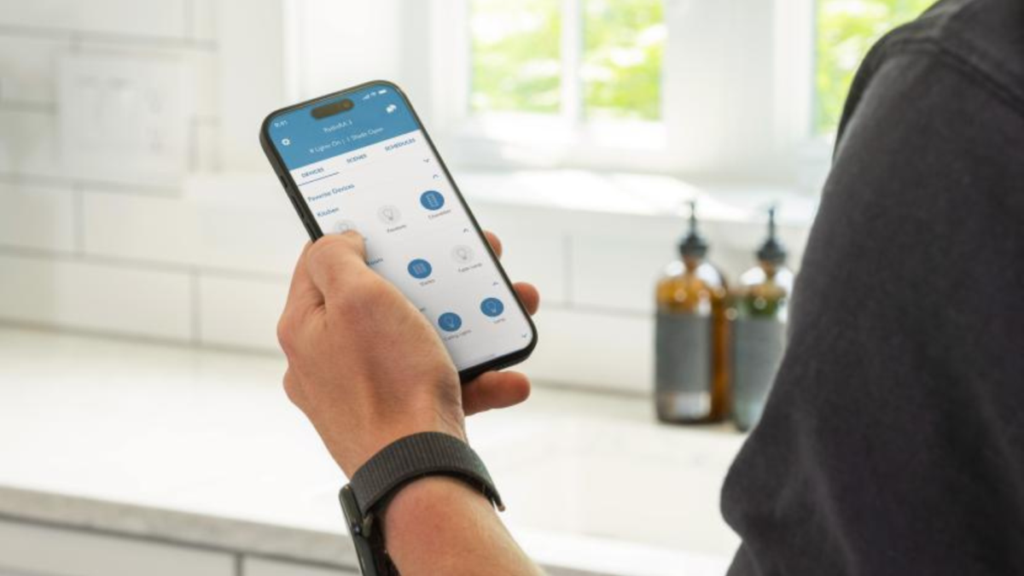 Person using Lutron smart home app to control lighting on smartphone in kitchen.