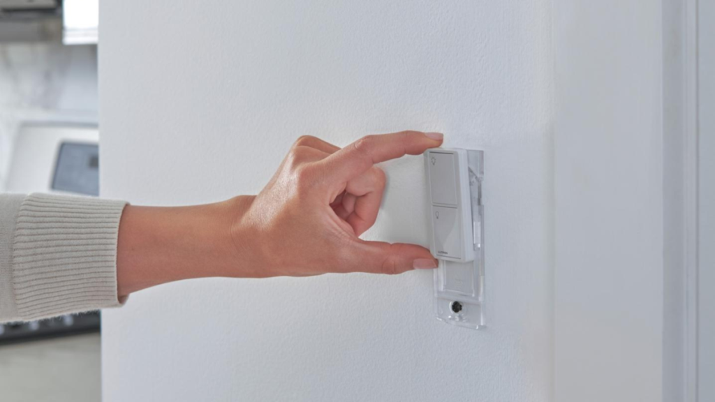 Hand adjusting Lutron wall keypad light control switch on interior wall.