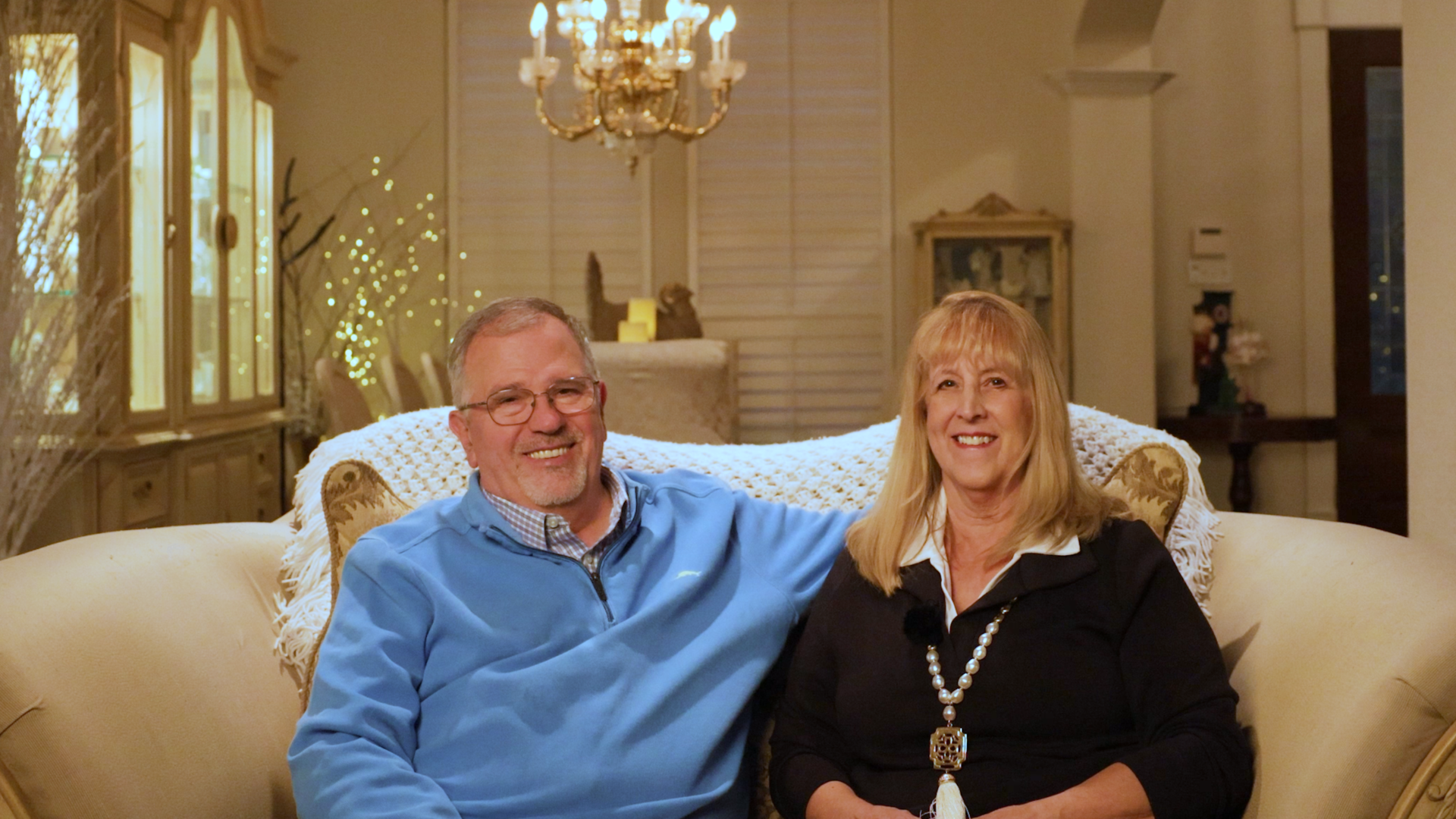 Married couple smiling at camera inside the living room of their custom estate renovated by Garabedian Properties.