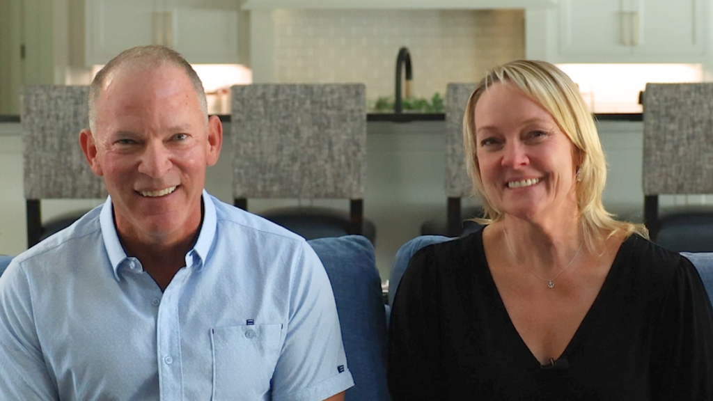 Married couple smiling at camera inside the living room of their custom estate built by Garabedian Properties.