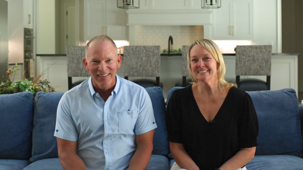 Married couple smiling at camera inside the living room giving their custom home builder reviews of their estate built by Garabedian Properties.