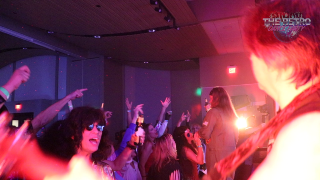 Guitarist on stage with people dancing on a large dancefloor.
