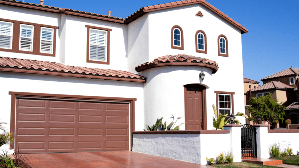 White stucco home with a clay tile roof, arched entry, and painted garage door, showing exterior finishes that require gentle low-pressure washing.
