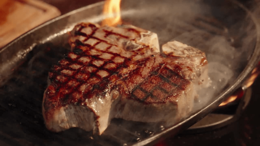 Delicious porterhouse steak on skillet being cooked.