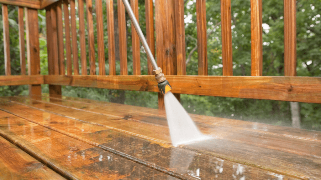 Pressure washer removing gray weathering from cedar deck boards, revealing the original wood tone beneath years of exposure.